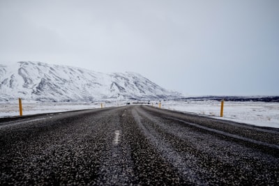 沥青道路附近山装满雪多云的天空下
